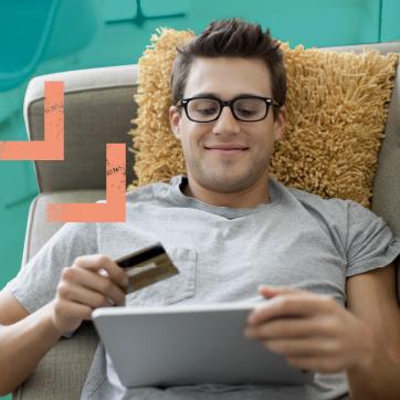 Man sitting on a couch with a credit card and tablet